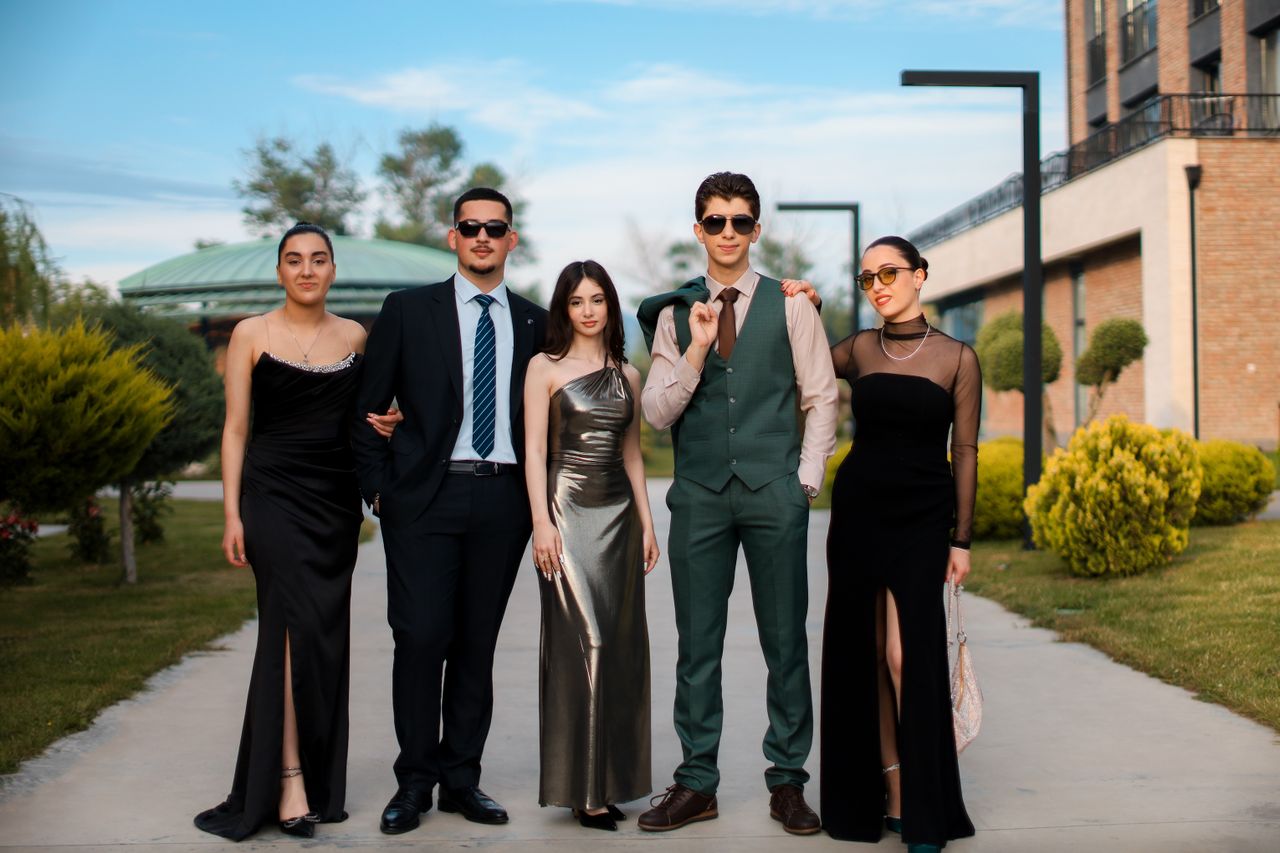 Services A stylish group of five adults in formal attire posing outdoors on a sunny day.